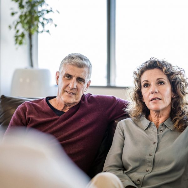 Mature couple looking at psychiatrist in office. Mental health professional is sitting with man and woman. They are wearing casuals.